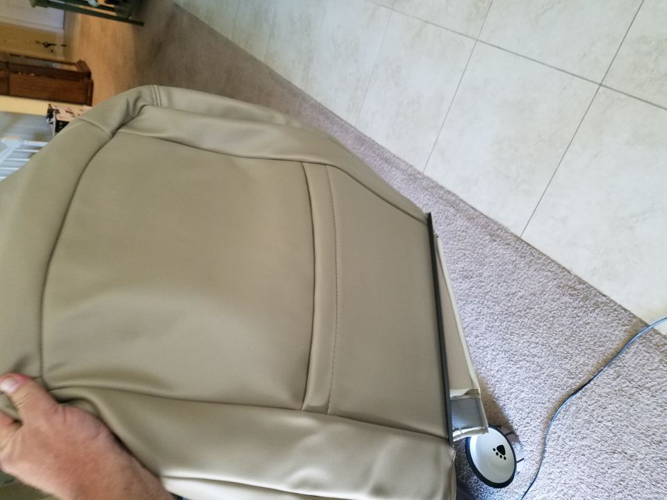 Tan leather car seat with visible stitching and metal trim