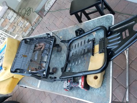 1994 Ford Bronco - Disassembled vehicle seats with yellow foam and black metal frames are laid out on a table.