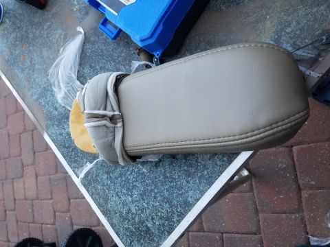 1994 Ford Bronco - A tan center console armrest is shown, likely for a vehicle interior, with stitching visible on the padded surface.