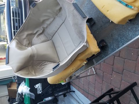 1994 Ford Bronco - A vehicle seat is disassembled on a table, with the front of a truck visible in the background.