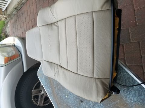 1994 Ford Bronco - A tan leather car seat with perforated inserts is shown, with a portion of a silver vehicle visible.