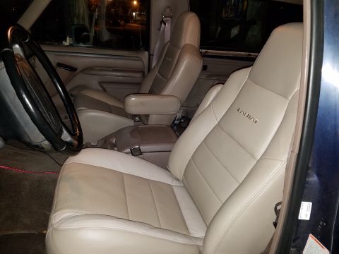 1994 Ford Bronco - Interior view of a truck's front seats, showing tan leather upholstery and a center console.