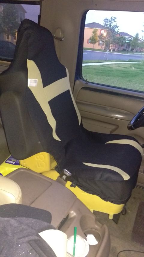 1994 Ford Bronco - Interior view of a vehicle's passenger seat with a seat cover and yellow containers below.