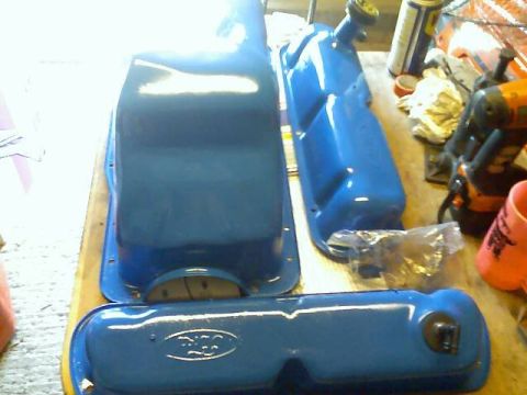 1989 Ford Bronco - Engine parts, likely a Ford oil pan and valve covers, are laid out on a workbench.