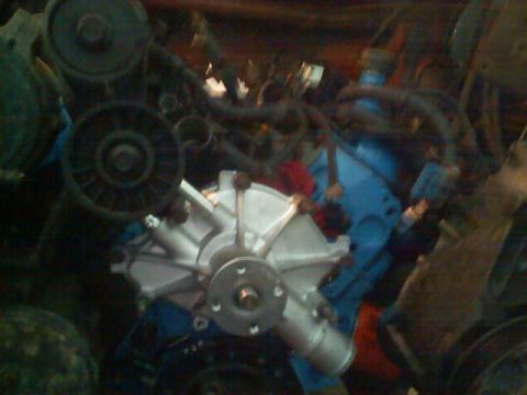 1989 Ford Bronco - Close-up view of engine parts, including a water pump and pulleys, with some blue painted components visible.