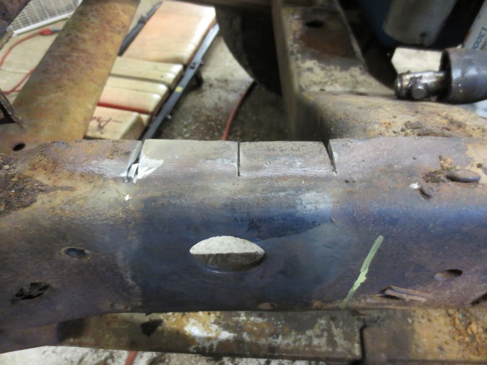Close-up of a rusty truck frame showing two parallel cuts made into the metal