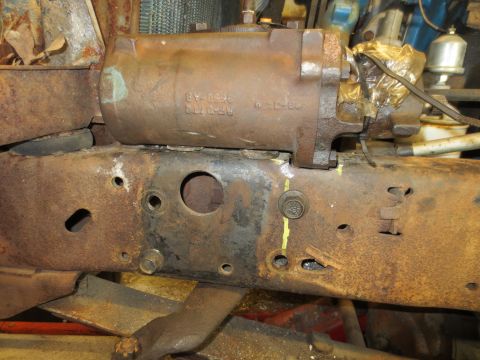 1967 Ford F-250 - This photo shows a power steering cylinder attached to a heavily corroded vehicle frame, with some parts wrapped in plastic.