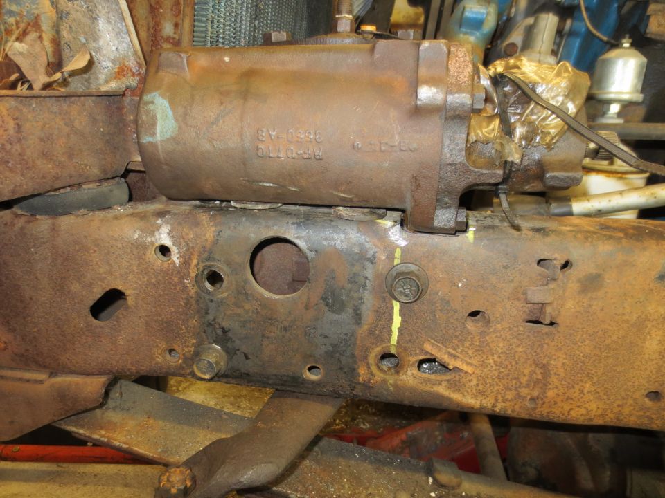 Close-up of a rusty power steering cylinder mounted on a heavily rusted truck frame