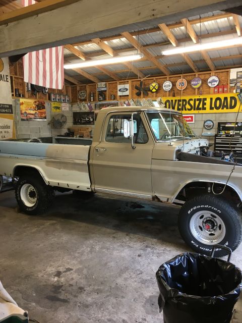 1967 Ford F-250 - A tan and white Ford F-Series truck sits in a garage with its hood open, showing signs of repair.