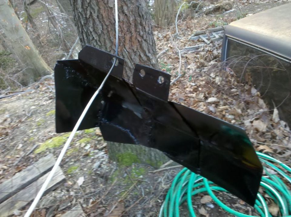 Black metal bracket bolted to a tree with a rope attached