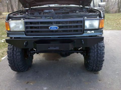 1989 Ford Bronco - This Ford Bronco features an aftermarket bumper and large off-road tires, with its hood raised.