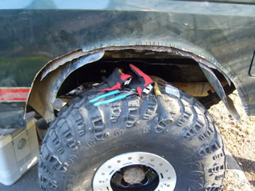 1989 Ford Bronco - Close-up view of a damaged wheel well, revealing rust and tools placed on the tire.