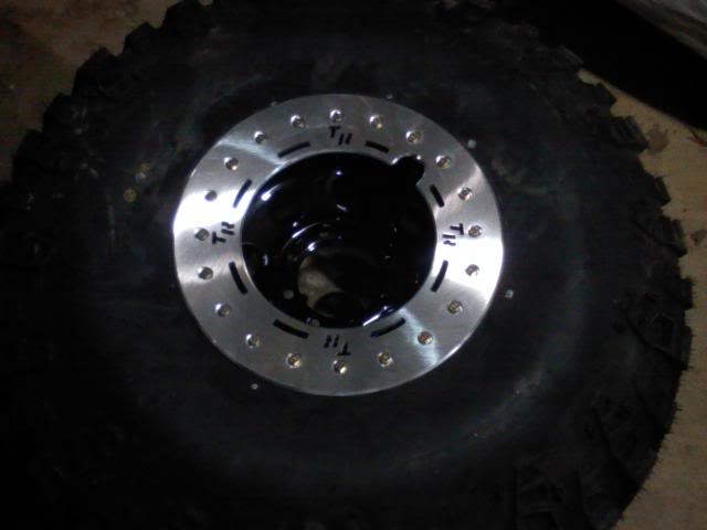 Tire with a silver wheel and black hub, showing bolt holes and 'TR' markings