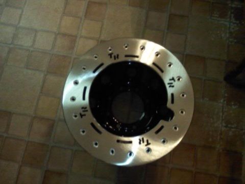 1989 Ford Bronco - A single brake rotor is shown on a tiled floor, with some markings visible on its surface.