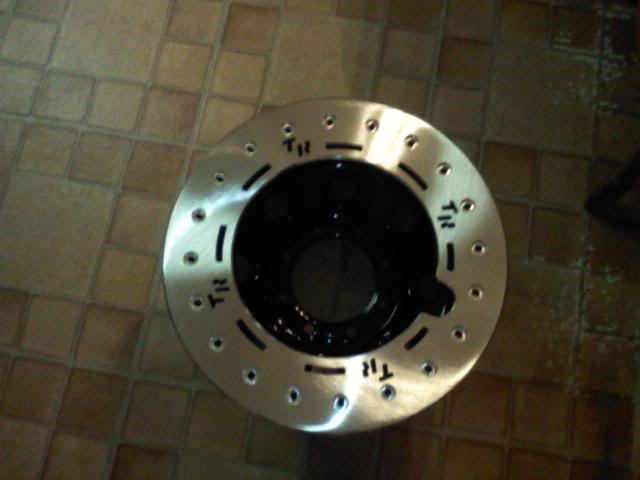 Brake rotor with 'TR' markings on a tiled floor
