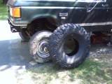 1989 Ford Bronco - A green Ford Bronco is shown with two tires, one mounted and one beside it.