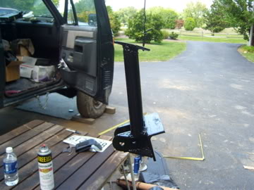 1989 Ford Bronco - A metal bracket is displayed next to the open door of a vehicle, with various items on a nearby table.