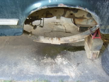 1989 Ford Bronco - Vehicle's rear suspension and wheel well detail, supported by jack stands.