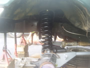1989 Ford Bronco - Close-up view of the suspension system of a green vehicle, undergoing maintenance.