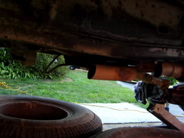 1989 Ford Bronco - Undercarriage view of a vehicle's exhaust system and a spare tire, with a visible Supermotors logo.