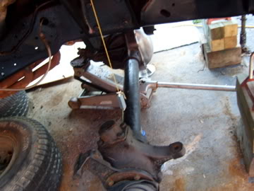 1989 Ford Bronco - Close-up view of a vehicle's undercarriage, supported by a jack, with the SuperMotors logo in the lower right corner.