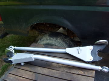 1989 Ford Bronco - Two suspension arms are shown in front of a dark vehicle's fender and tire.