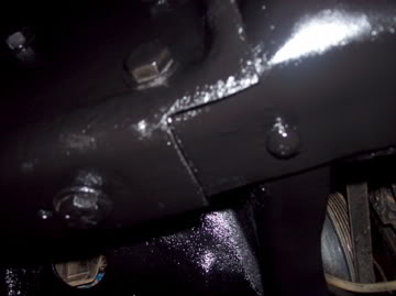 1989 Ford Bronco - Close-up view of a vehicle's undercarriage, showing structural components and a tire tread.