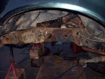 1989 Ford Bronco - Close-up view of heavily rusted vehicle frame and suspension parts, indicating significant wear and tear.