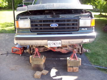 1989 Ford Bronco - Front view of a green Ford Bronco with its hood open, raised on jack stands for maintenance.