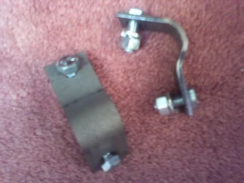1989 Ford Bronco - Two metal brackets with hardware are shown against a textured background.