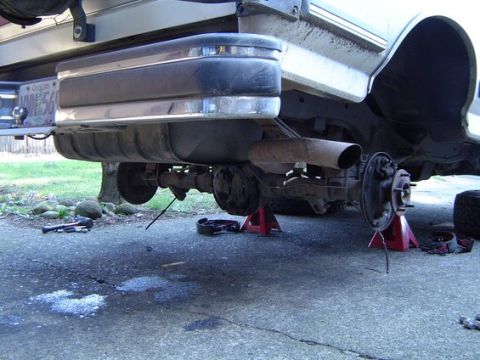 1988 Ford Bronco - Rear axle and suspension of a 1988 Ford Bronco undergoing maintenance, with brake drum removed and vehicle supported by jack stands.