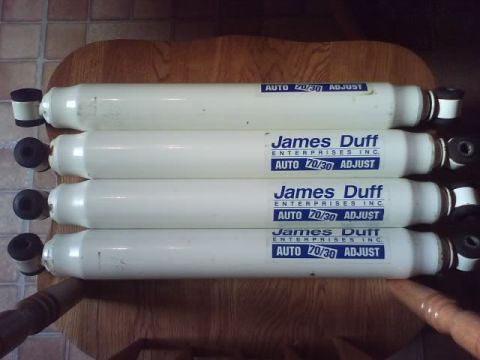 1989 Ford Bronco - Four James Duff Enterprises adjustable shock absorbers are shown on a wooden surface.
