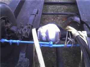 1989 Ford Bronco - Close-up of a rear axle assembly, blue suspension parts and a SuperMotors watermark.