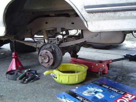 1988 Ford Bronco - Servicing the rear axle of a vehicle, with brake components disassembled and tools laid out.