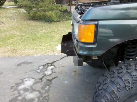 1989 Ford Bronco - Close-up of the front corner of a green Ford Bronco, showing its bumper and tire.