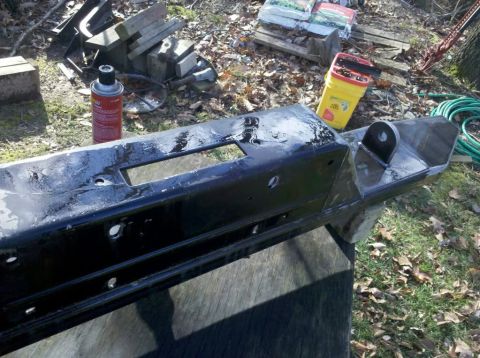 1989 Ford Bronco - A black metal bumper with a tow hitch is shown outdoors, resting on a wooden surface.