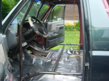1989 Ford Bronco - The interior of a vehicle is shown with a prominent roll cage and stripped-down appearance.
