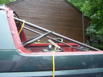 1989 Ford Bronco - Close-up view of a vehicle's interior roll cage structure, yellow tie-down straps and a visible SuperMotors watermark.