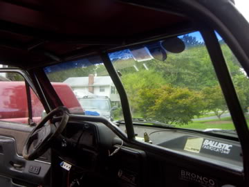 1989 Ford Bronco - The interior of a vehicle is visible, a roll cage and a sticker on the dashboard.