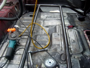 1989 Ford Bronco - Roll cage installation in progress inside a vehicle, with tools and an angle grinder present.