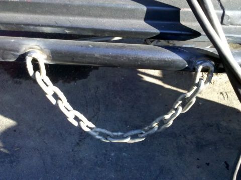 1989 Ford Bronco - A chain is attached to a metal bar, likely part of a vehicle or trailer component.