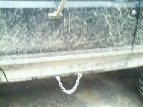 1989 Ford Bronco - A chain is attached to the lower body of a mud-covered vehicle.