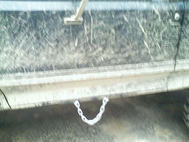 side of a dirty vehicle with a chain attached to the frame