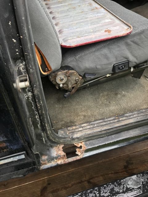 1992 Ford Bronco - The interior of this vehicle shows a worn seat and extensive rust damage on the door sill, indicating a need for repair.