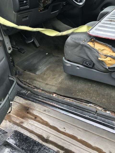 1992 Ford Bronco - The interior of a 1992 Ford Bronco reveals a worn driver's seat and floor mats.