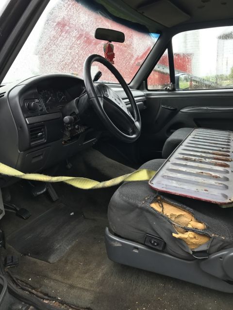 1992 Ford Bronco - Interior view of a 1992 Ford Bronco, showing the dashboard, steering wheel, and a damaged driver's seat.