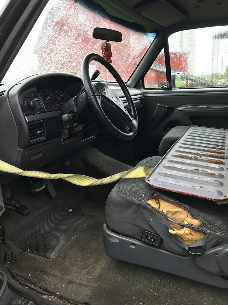 1992 Ford Bronco interior with ripped driver's seat and dashboard