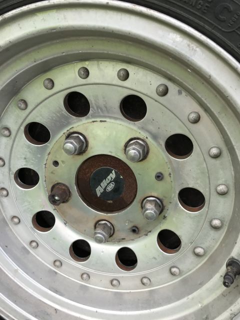 1992 Ford Bronco - A close-up view of a vehicle's alloy wheel, showing the lug nuts and a brand marking.