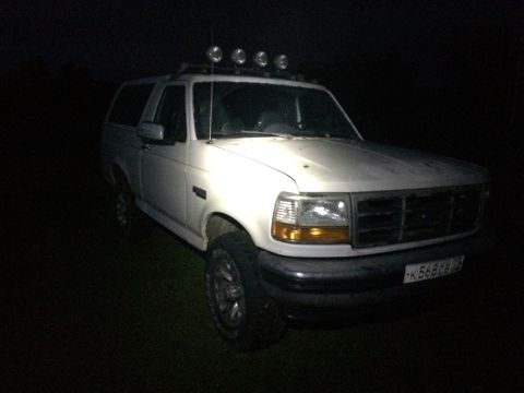 1993 Ford Bronco - A white 1993 Ford Bronco is parked outdoors at night, equipped with four roof-mounted lights.