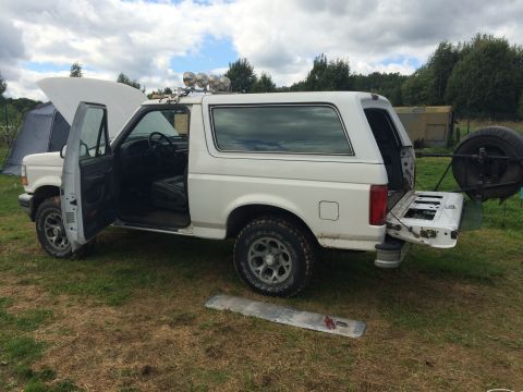 1993 Ford Bronco - White 1993 Ford Bronco parked outdoors with doors and hood open, spare tire visible on the rear.
